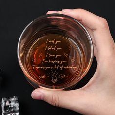 a person holding a glass with some writing on it