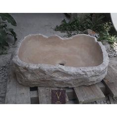 a stone sink sitting on top of wooden pallets