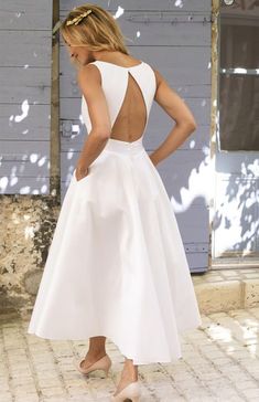 a woman in a white dress standing on a brick floor with her back to the camera