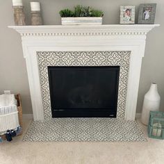 a living room with a fire place and white fireplace mantel in front of a gray wall