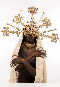 a woman with an elaborate head piece on her face and arms, wearing gold jewelry