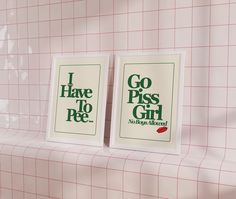 two posters are hanging on the wall next to each other in a room with pink tiles