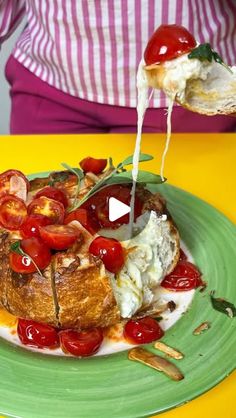 a person pouring cheese on top of a plate with tomatoes and other food items in it