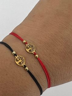 two bracelets that are on someone's arm, one is gold and the other has red string