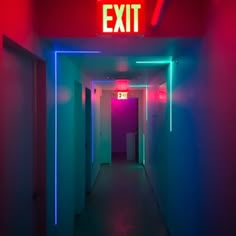 an exit sign that is lit up in the middle of a hallway with neon lights