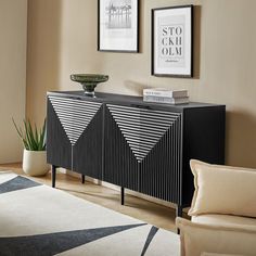 a black and white sideboard in a living room with two pictures on the wall