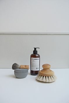 a white counter top with a bowl, brush and soap dispenser