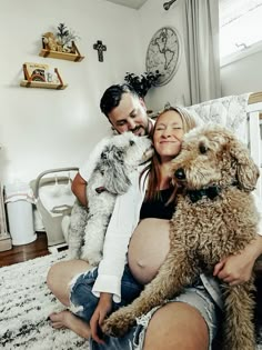 a man and woman sitting on a bed with two dogs