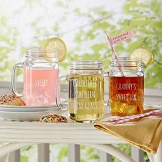 three mason jars filled with liquid sitting on a table next to donuts and sprinkles