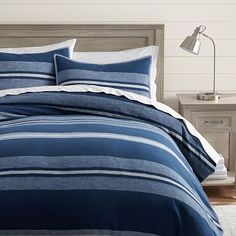 a bed with blue and white striped comforters