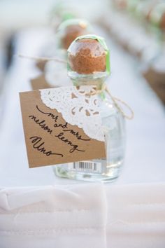 a small bottle filled with sand sitting on top of a white tablecloth covered table