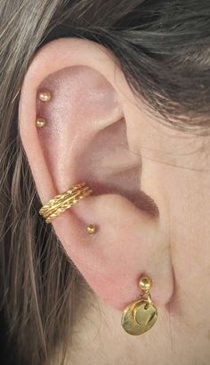 a close up of a person's ear with two gold rings on top of it