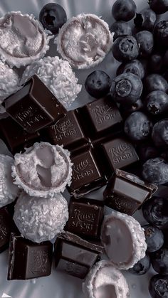 chocolates and blueberries on a plate next to some other food items, including grapes