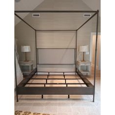 a four poster bed in a bedroom with white walls and beige carpeted flooring