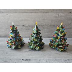 three small ceramic christmas trees on a table