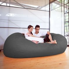 a man and woman sitting on a bean bag chair in the middle of a room