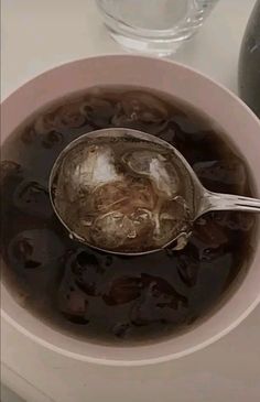 a white bowl filled with black liquid and a spoon