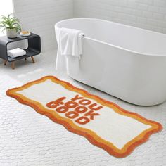 a bath tub sitting next to a rug that says you look good on the floor