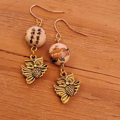 2¼ Inch Long Gold Tone Metal Owl Charm Earrings. These Earrings And Handmade On Gold Tone Metal Findings With A Tan Lotus Flower Bead. $10.00 +S&H #Countrygypsyor Adjustable Nickel-free Beige Earrings, Nickel-free Beige Earrings As Gift, Nickel-free Beige Earrings For Gifting, Nickel-free Beige Dangle Earrings, Nickel-free Beige Earrings For Gift, Beige Nickel Free Dangle Earrings, Beige Nickel-free Dangle Earrings, Beige Round Beads Earrings As Gift, Beige Round Beads Earrings For Gift