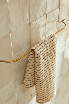 two towels hanging on a towel rack in a tiled bathroom with white tile walls and flooring