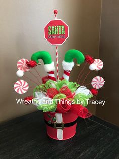 candy canes and santa hats are in a red bucket on a table next to a stop sign