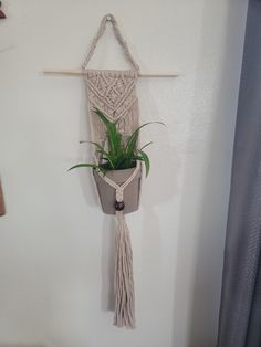 a macrame plant hanging on the wall with a potted plant in it