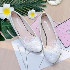 a pair of white shoes sitting on top of a table next to flowers and cards