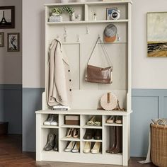 a white coat rack with shoes and purses on it next to a wall filled with pictures