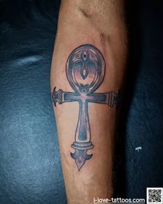 a cross tattoo on the leg of a person with an eye and key in it