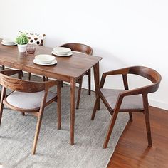 a dining room table with chairs and plates on top of it in front of a white wall