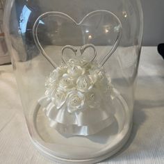 a heart shaped vase with flowers in it on top of a white cloth covered table