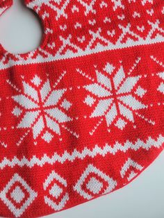 a red and white knitted bib with snowflakes on it's side