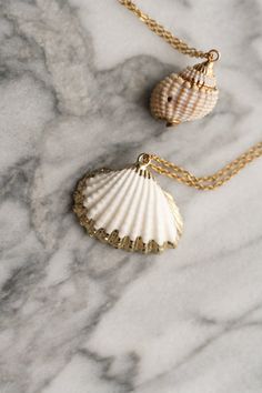 This Syrena necklace is a mermaidcore essential. It features a natural shell with gold painted edges for the most ethereal look. Perfect for your long hot mornings on the beach with sandy toes and a hibiscus flower tucked behind your ear, or for lazying on the Italian lakeside, roaming villa estates up and down Lake Como. Pair with semi sheer dresses, plenty of ruffles and soft mermaid tail silhouettes for the ultimate mermaidcore look. Gold chain is 18K gold plated. Select either the spiral she Gold Shell Jewelry For Beach, Gold Shell Necklaces For Summer, Summer Gold Shell Necklaces, Gold Ocean-inspired Shell Necklace For Vacation, Summer Gold Shell Necklace, Beachy Gold Shell-shaped Jewelry, Beachy Gold Shell Jewelry, Cream Shell Jewelry For Gifts, Cream Shell Jewelry For Gift