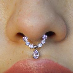 a woman's nose with a tear shaped diamond necklace attached to the side of her nose