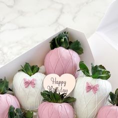 pink and white strawberries in a box with a happy birthday sign on it's side