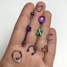 a person's hand holding several different types of fake flowers and piercings on them