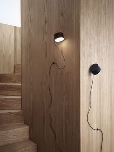 a light that is on the side of a wooden wall next to some wood steps