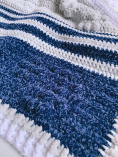 a blue and white crocheted blanket laying on top of a bed