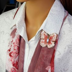 a close up of a woman's shirt with a butterfly brooch on it