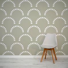 a white chair sitting in front of a wall with an art deco pattern on it