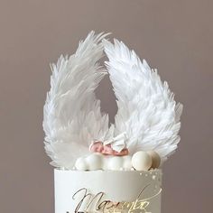 there is a cake with white feathers on the top and gold writing on the bottom