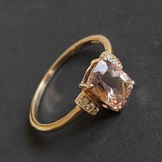 an engagement ring with a pink diamond and two diamonds on the side, sitting on a black surface