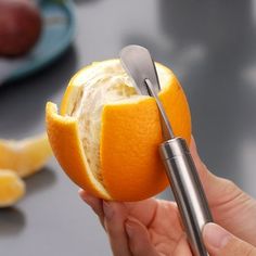 a person holding an orange with a fork in it