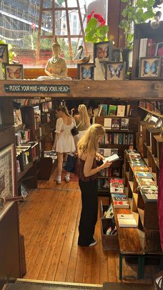 two women are looking at books in a book store while another woman looks on from the second floor