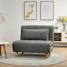 a grey chair sitting on top of a rug in a living room next to a table