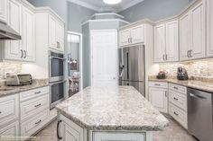 a large kitchen with white cabinets and granite counter tops, along with stainless steel appliances