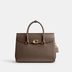 Our Broome has all the effortless cool of its namesake Soho street. The spacious foldover silhouette is crafted of luxe refined leather with a high shine finish and secures with our pushlock “C” closure. Featuring pockets inside and out for easy organization and room for a 16” laptop carry it by hand or use the detachable strap to wear it crossbody. | Coach Broome Carryall Bag 36 - Women's - Brass/dark Stone Coach Work Bags For Women, Latest Coach Handbags, Coach Bags 2021, Luxury Handbags Coach, Coach Bags Handbags Coach, Coach Purse Coach, Coach Tatum Carryall 40, Studio Shoulder Bag Coach, Coach Purses Coach