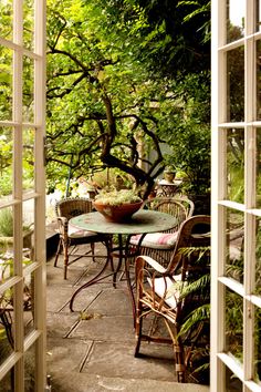 an outdoor table with chairs and a bowl of food on it in the middle of a patio