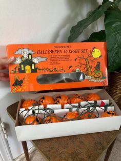 an open halloween light set with pumpkins in it and a hand holding the box