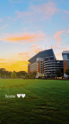 the sun is setting over a field with buildings in the background and a heart - shaped word that reads, home